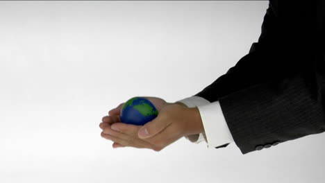 a pair of cupped hands hold a small globe