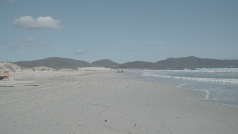 toma estática de una playa con montañas y gente en el fondo