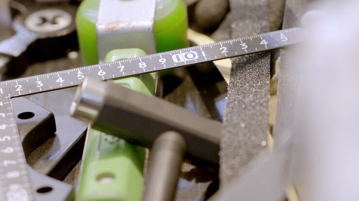 Close-up of a variety of tools and parts in a workshop, highlighting a ruler, bolts, and other essential components used for detailed assembly and maintenance work, showcasing precision craftsmanship.