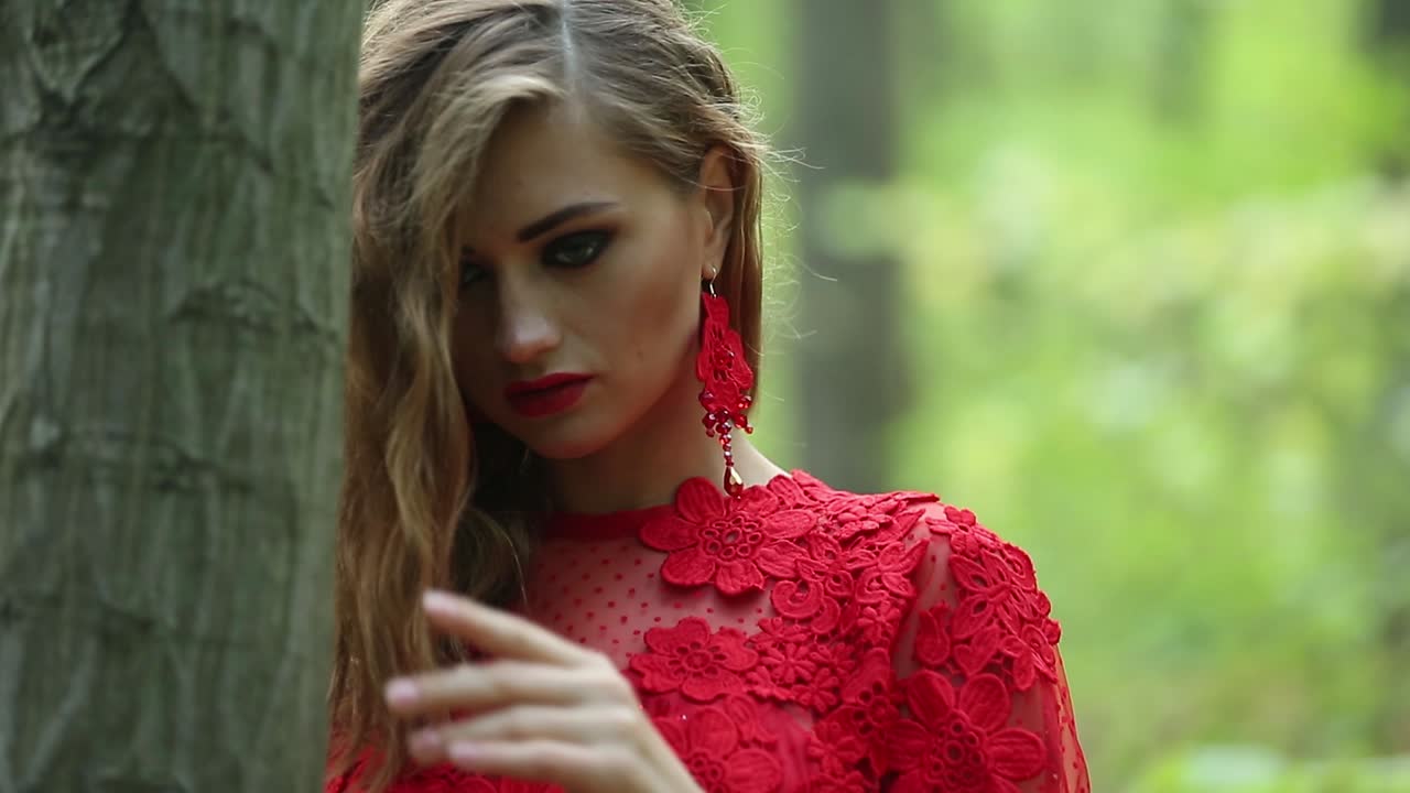 Pretty Woman Explores Beautiful Forest. Pretty woman in a long red dress explores beautiful forest