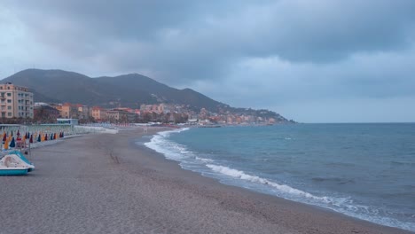 panorama of varazze beach at sunset with all its typical closed umbrellas, no people and very cloudy sky from a thunderstorm