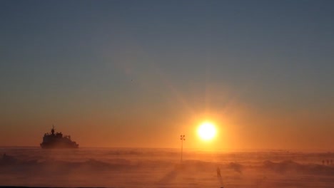 blizzard conditions engulf an ice floe with a us coast guard ship distant