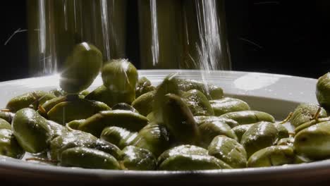 Aceitunas-De-Mesa-Cayendo-En-Un-Plato-Blanco