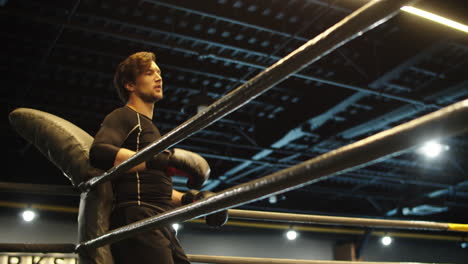 Handsome-fitness-man-having-rest-in-sport-club.-Boxer-standing-on-boxing-ring