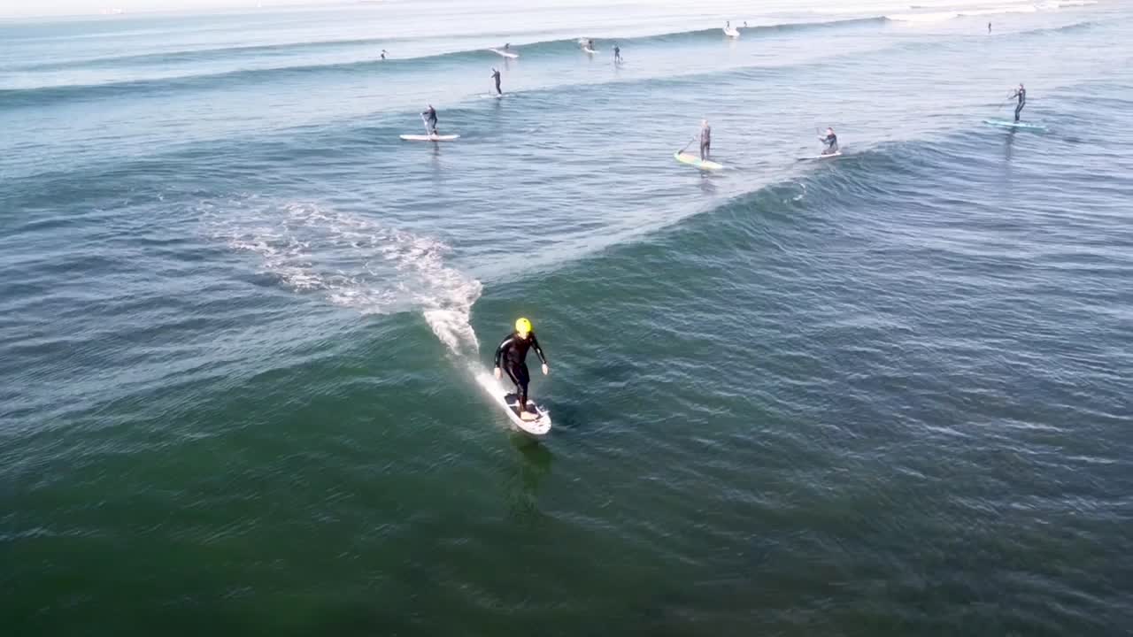 hydro foiler surfing wave behind watercraft filmed with drone