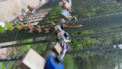 Rusted-heart-shaped-love-lock-over-on-a-bridge-handrail---vertical