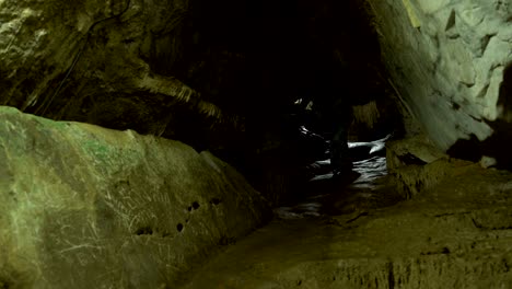 a woman is walking along a tunnel in a cave