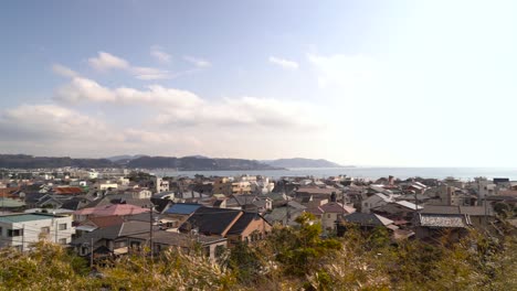 houses built in the small japanese seaside town of enoshima in japan with bright sun in the background - right panoramic shot