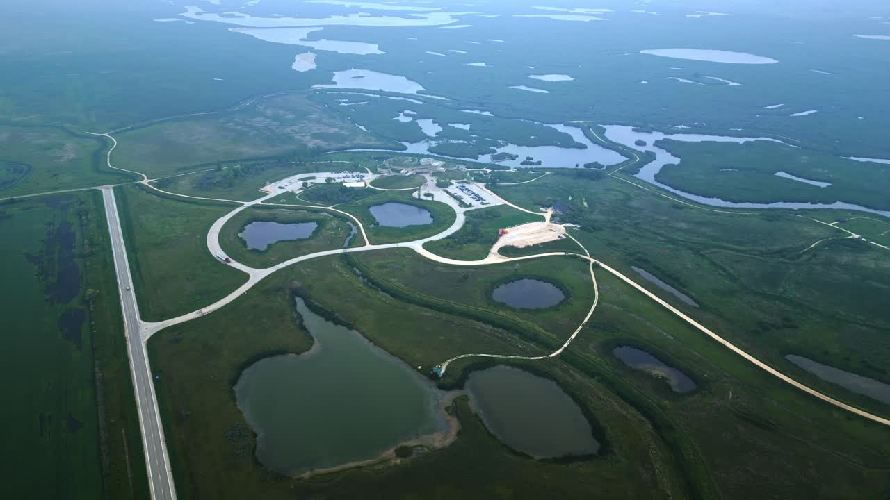 Overhead drone frames circular green-roof building within sprawling wetlands