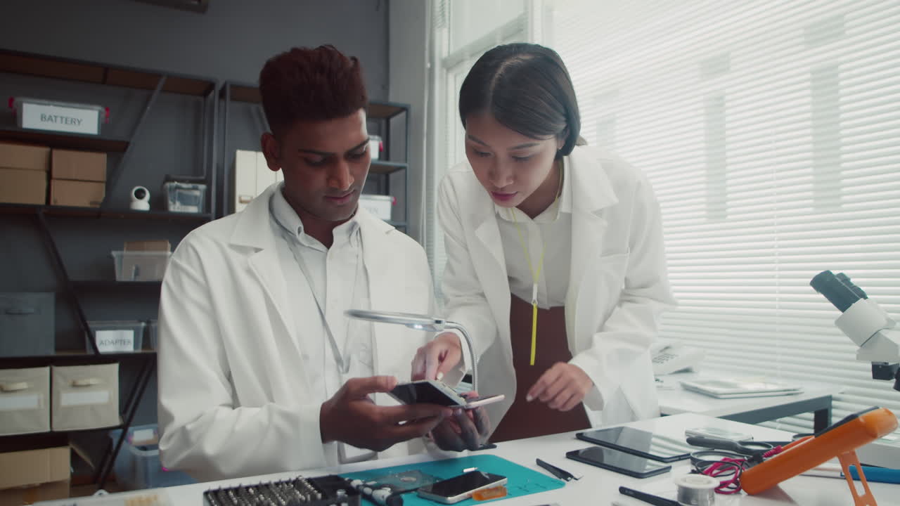 Coworkers Examining Broken Mobile Phone at Service Center