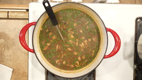 arroz salvaje y sopa de champiñones coronada con cebolletas recién cortadas hirviendo a fuego lento y al vapor en una olla en la estufa y lista para servir - vista superior de la serie de arroz salvaje