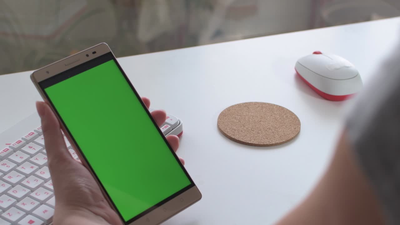 las manos de la mujer sosteniendo un móvil con pantalla verde