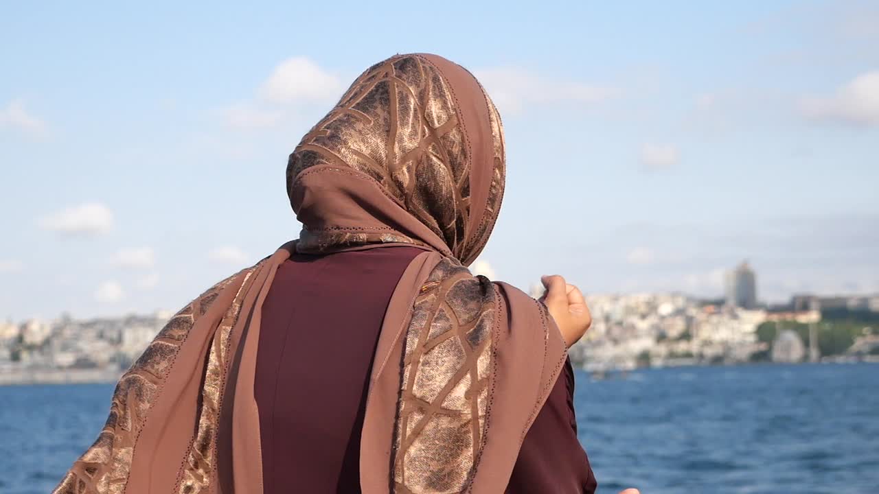 Woman in Hijab Overlooking City by the Water