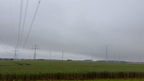 power lines and wind turbines in a cloudy rural landscape