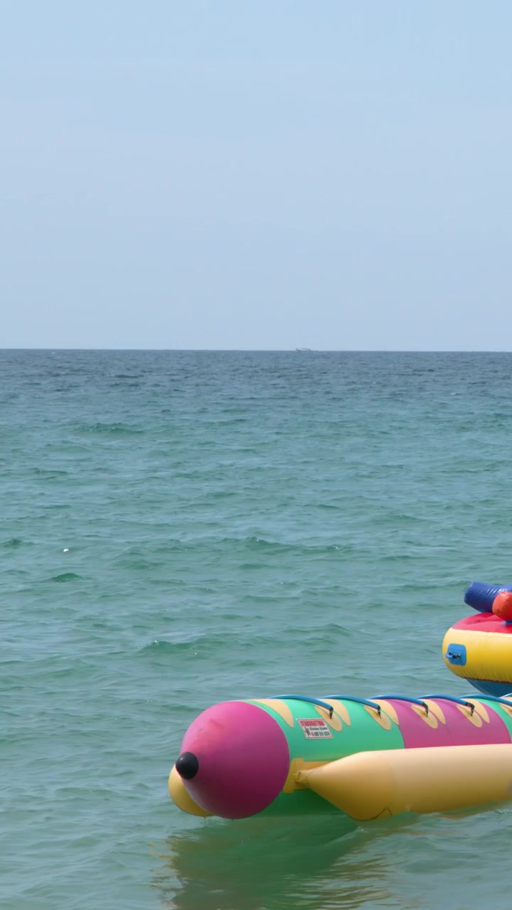 A vibrant inflatable banana boat floats on calm turquoise ocean water under bright daylight