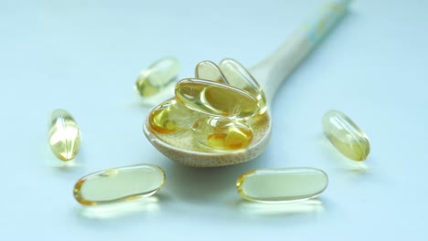 fish oil supplement on a wooden spoon on white ,