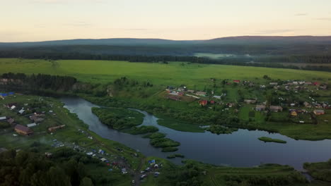 vista aérea de una pintoresca aldea rusa junto a un río al atardecer