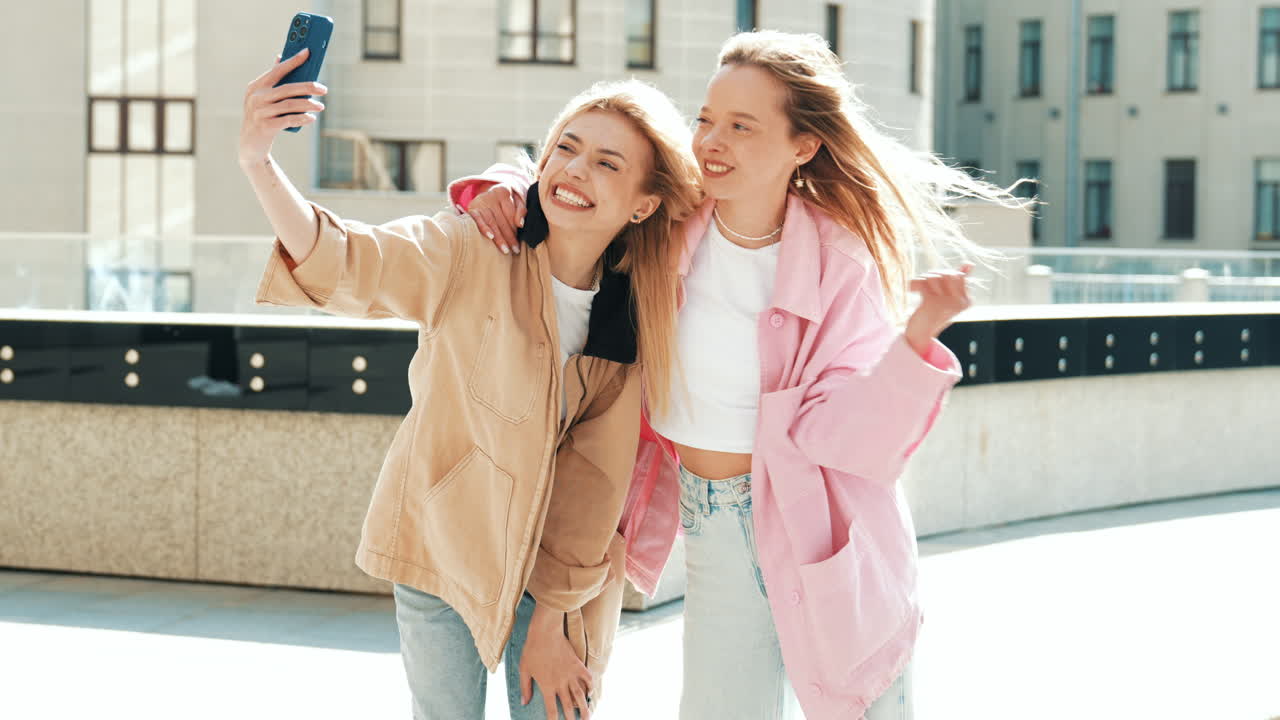두 명의 행복한 젊은 여성들이 야외에서 셀피를 찍고 있습니다.