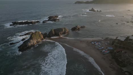 aerial rotates over golden beach at sunset, tourists enjoy sea waves