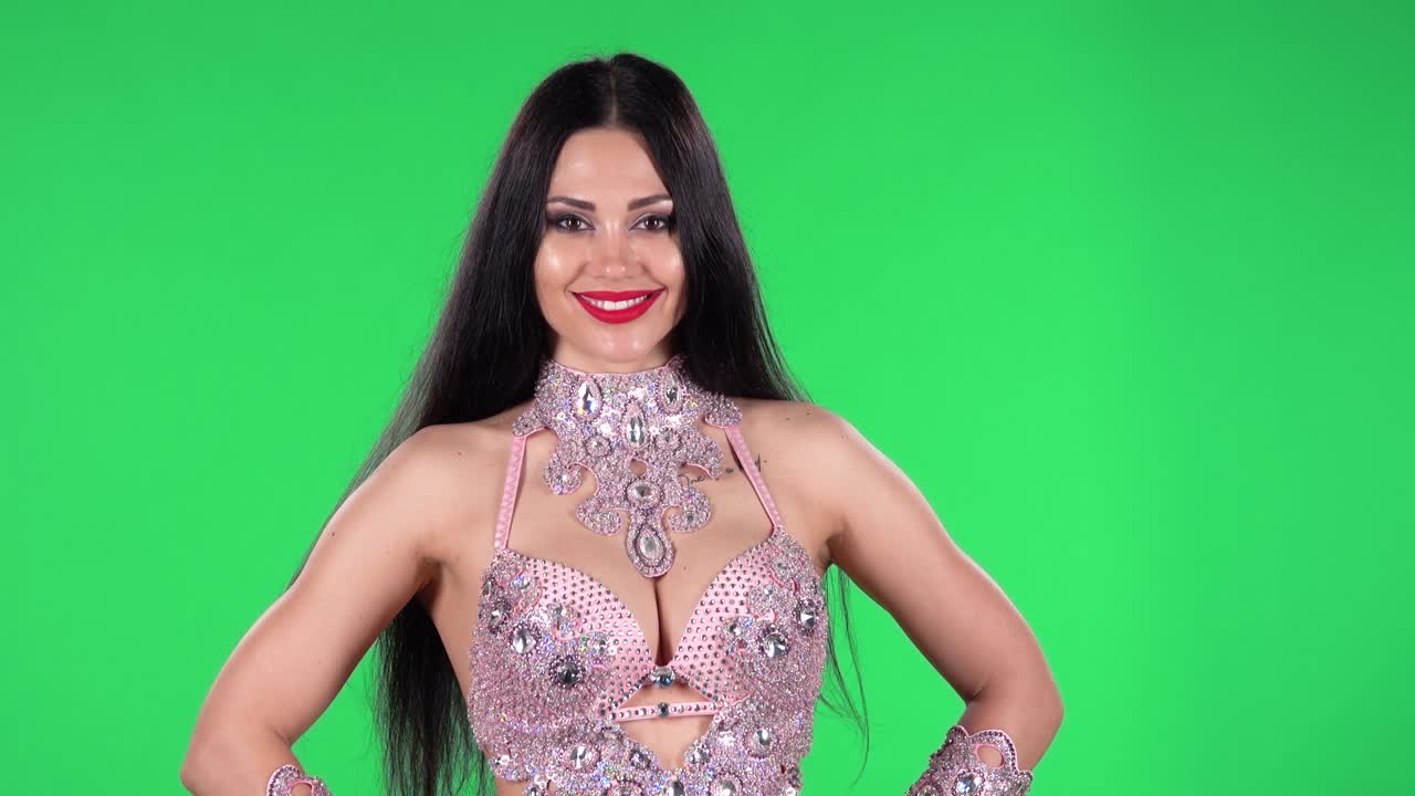 Portrait of beautiful woman in a chic dress for oriental dances in stones and rhinestones is looking straight and smiling. Green screen