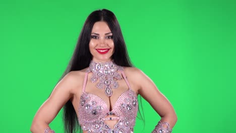 portrait of beautiful woman in a chic dress for oriental dances in stones and rhinestones is looking straight and smiling. green screen