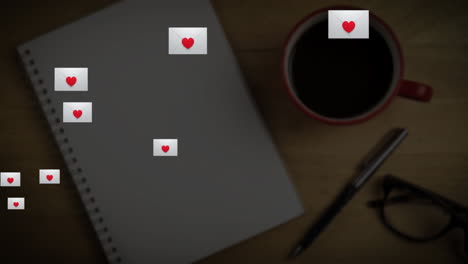 sobre múltiple con icono de corazón flotando contra el libro, la taza de café y los vasos en la superficie de madera