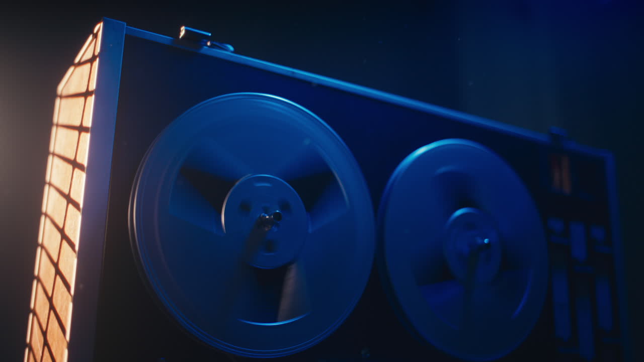 A vintage tape recorder spinning spools in a blue light