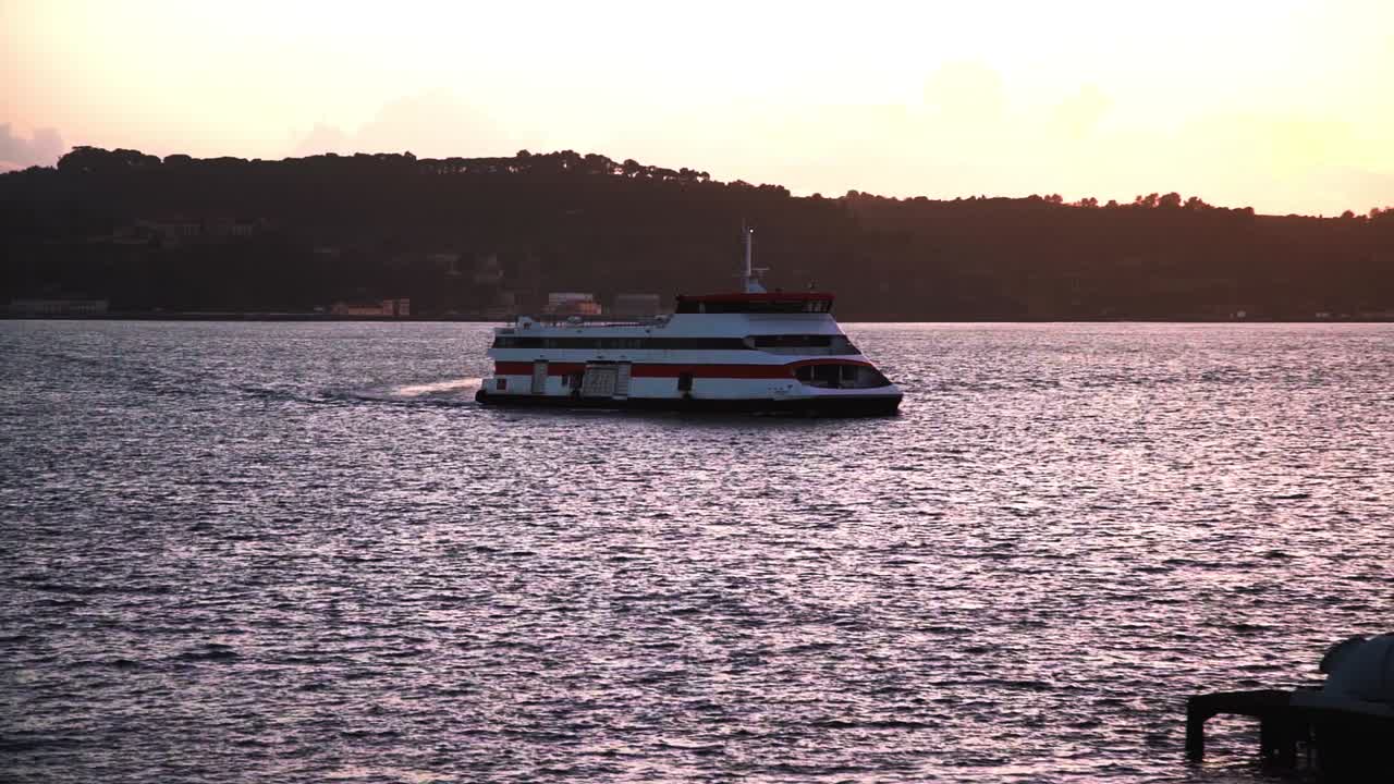 ferry en el río tejo al atardecer con fábricas en segundo plano.