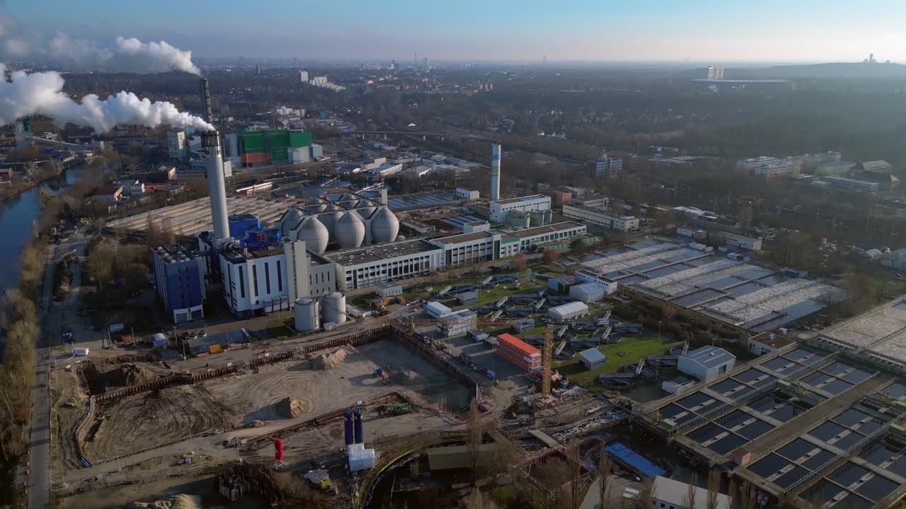 Wastewater treatment plant purifying urban water showing sedimentation tanks, aeration tanks and clarifiers. Majestic aerial view flight tilt down drone