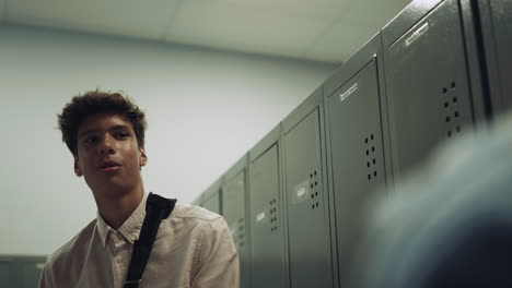 pretty indian boy standing at lockers school hall closeup. teen communication.