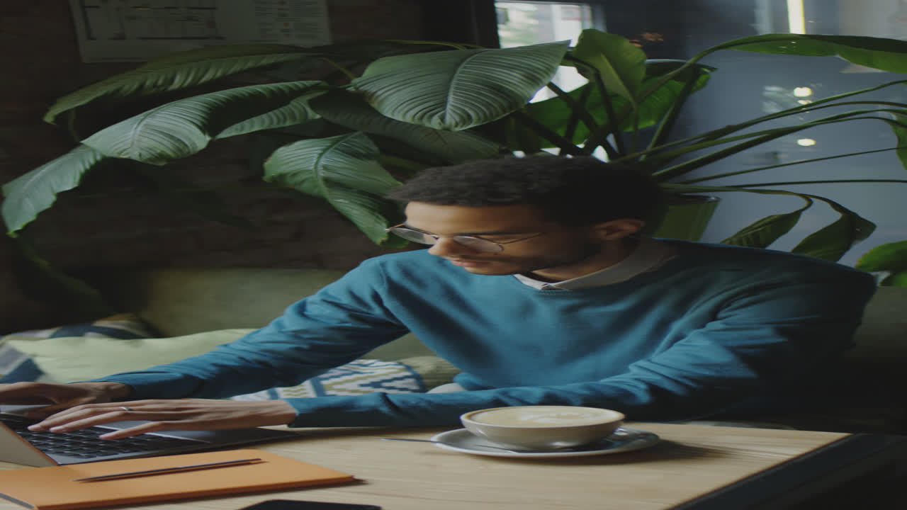 Male Freelancer Using Laptop in Coffeeshop