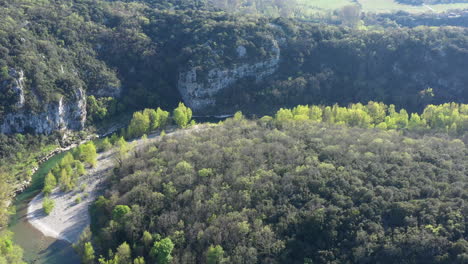 Winding-Herault-river-surrounded-by-forest-aerial-shot-spring-season-sunny-day