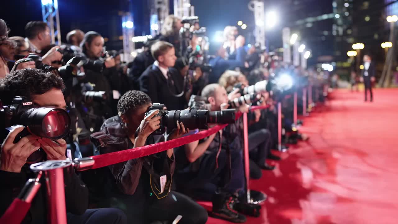 Low-angle shot of photographers capturing a red carpet event, resembling a video scene