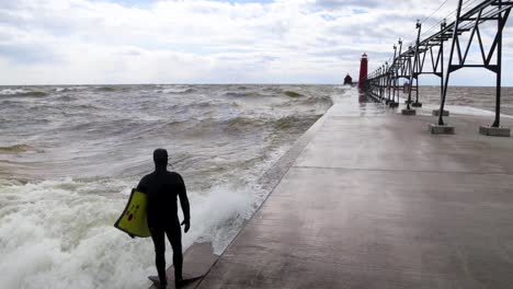 Surfista-Buceando-En-El-Lago-Michigan-Desde-El-Muelle-En-Grand-Haven,-Michigan