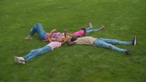 joyful multiethnic family lying on grass in circle