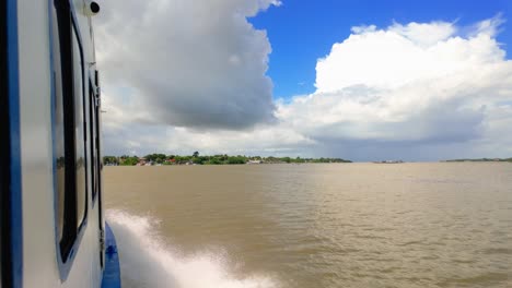 view from a moving boat on a wide river under a cloudy sky