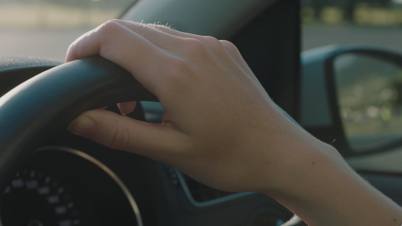 mujer conductor manos en el volante conduciendo un coche en la ciudad en la carretera en la hora pico viajando a destino al atardecer