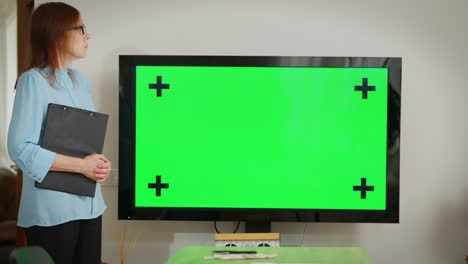 monitor de pantalla verde en la oficina con la mujer caucásica de pie a la izquierda hablando. conferencia web chromakey en el interior con confiado gerente inteligente planificación de proyectos tormenta de ideas en línea.