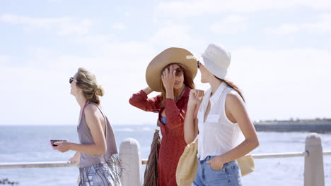 three young women tourists on summer vacation walking on beach promenade