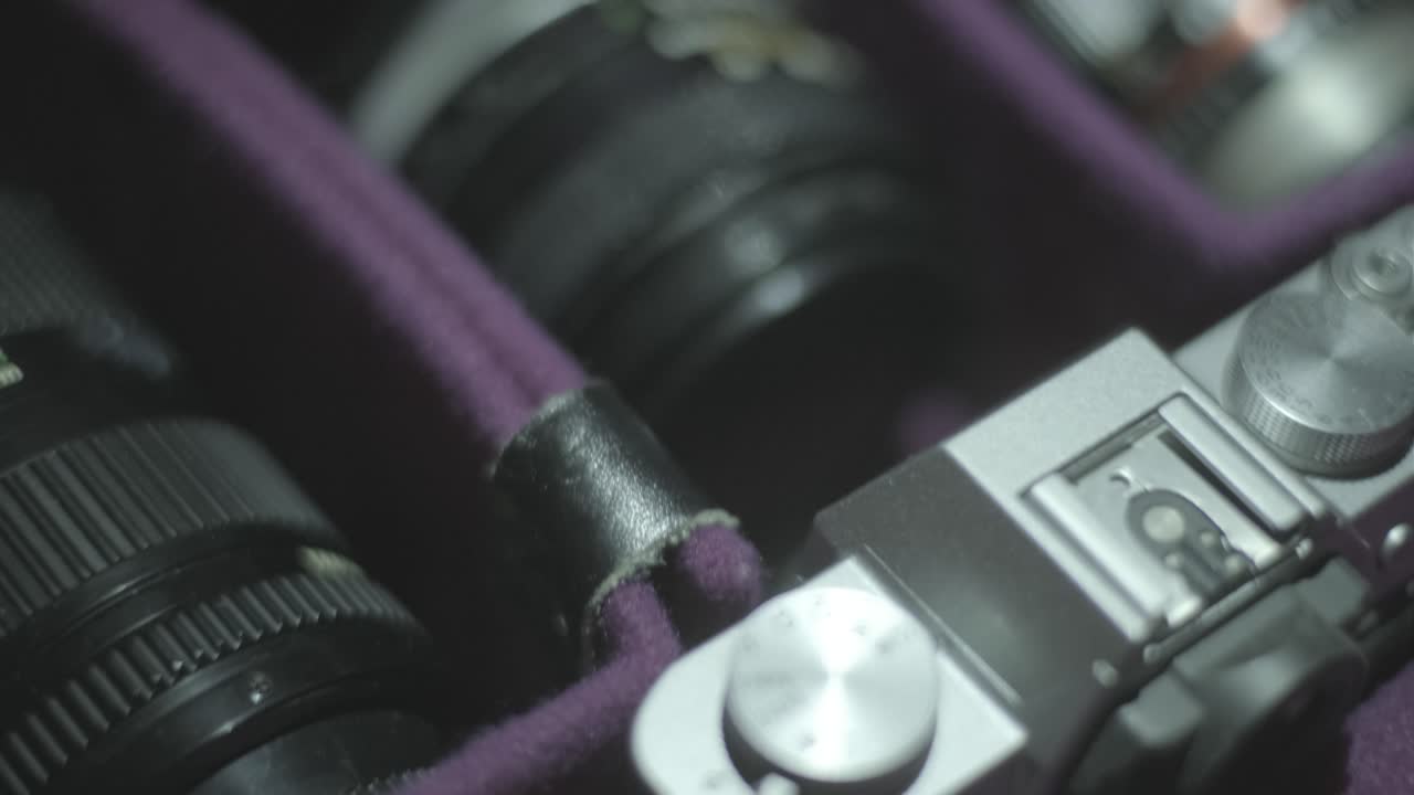 4k zooming out shot of a retro camera bag with retro camera lens, off focus