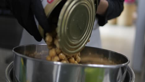 Pouring-Can-Of-Chickpeas-Garbanzo-Beans-Into-Metal-Bowl-Close-Up