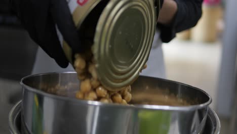verter una lata de garbanzo de garbanzo en un cuenco de metal de cerca