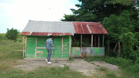 Boy-standing-in-front-of-Small-cottage-in-a-Caribbean-country