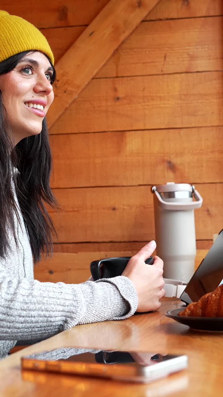 Giovane donna che sorride e naviga sul tablet con caffè e croissant