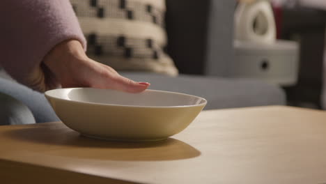 close up de la mujer en casa vertiendo tortilla o papas fritas de maíz de un paquete en un cuenco en la mesa