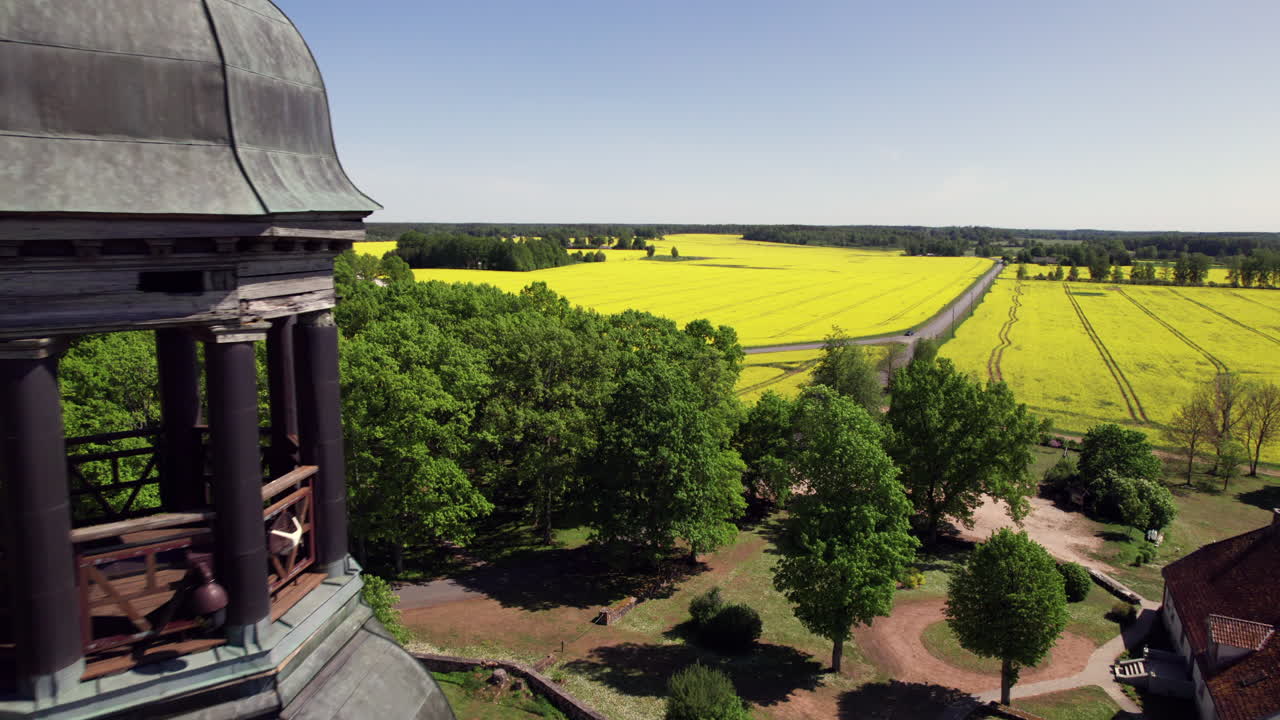 Flying past Burtnieku Church tower surrounded by rapeseed field