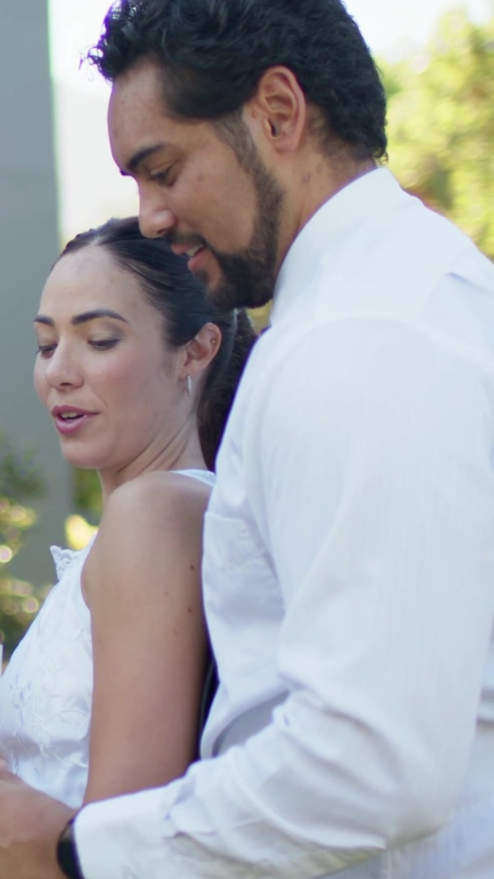 Vídeo vertical: Mulher sorrindo com vestido roxo brindando com taça, mãos se tocando à direita, espaço para texto.