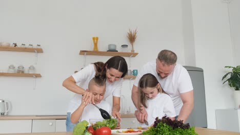 a happy european family prepares a vegetable salad together in a modern indoor kitchen a happy european family prepares a vegetable salad together in a modern indoor kitchen cooking dinner with organic vegetables