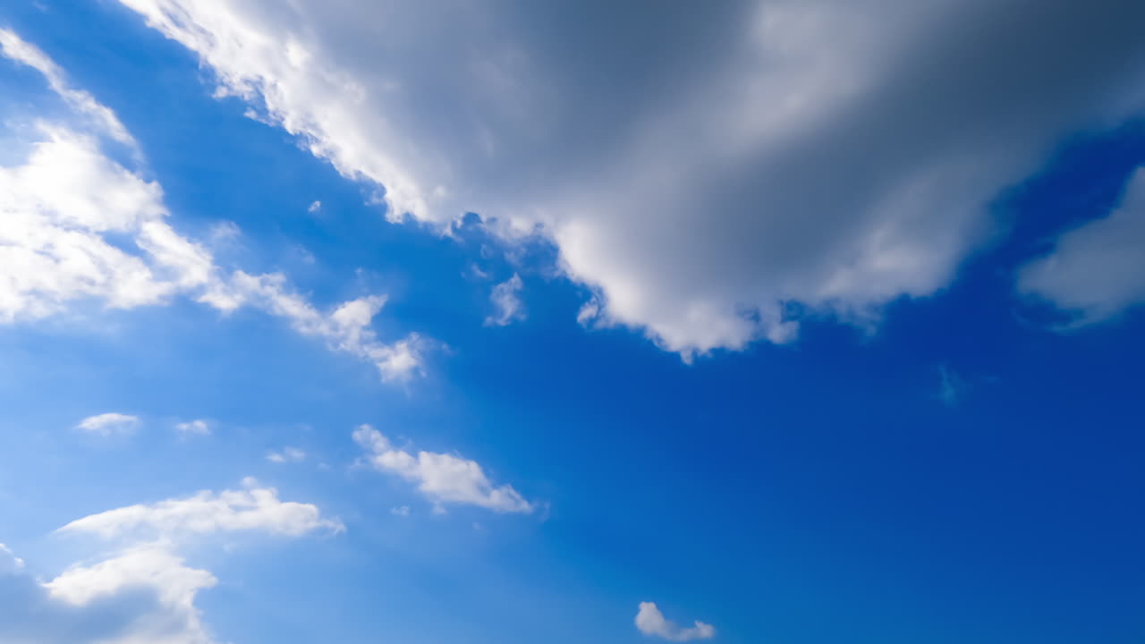 Transforming white clouds in the atmosphere. Azure summer sky with bright sun and clouds. Low angle view. Timelapse.