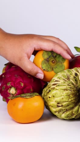 manos seleccionando frutas de dragón y caqui